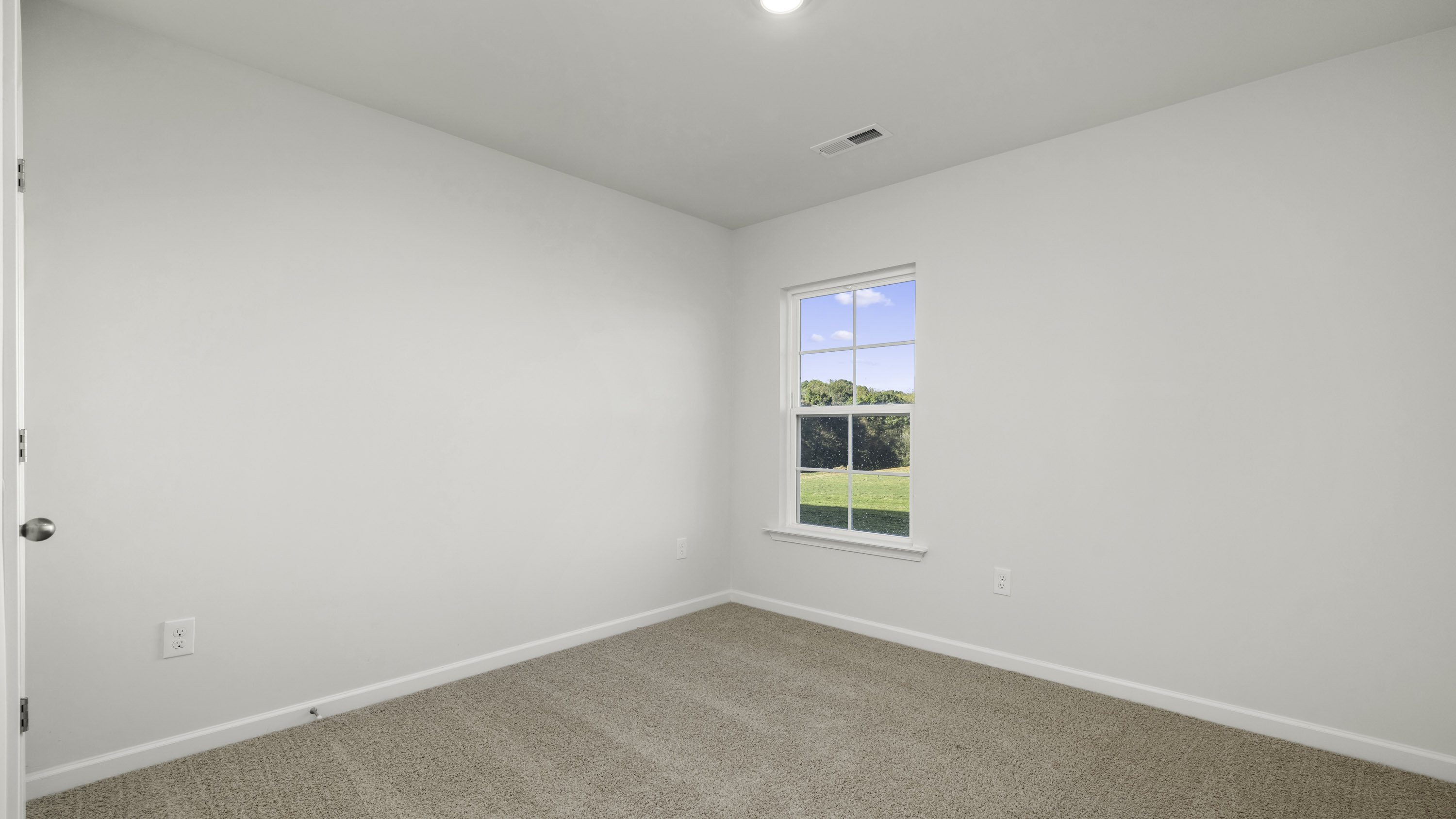 Neutral-toned carpeting, crisp white walls, and a single-hung window featuring outdoor scenery