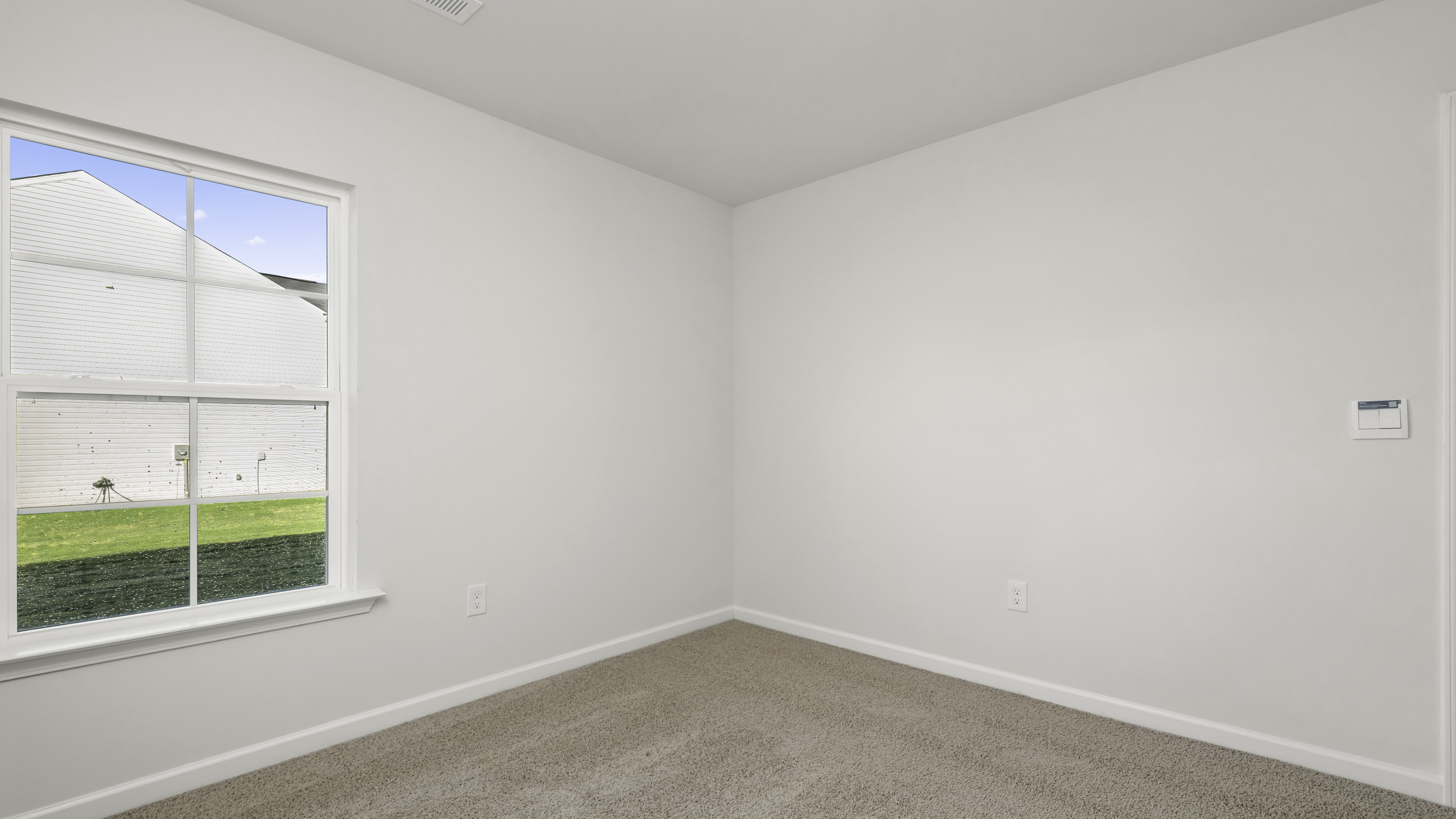 Interior room featuring neutral wall paint, wall-to-wall carpeting, and a multi-pane grid window