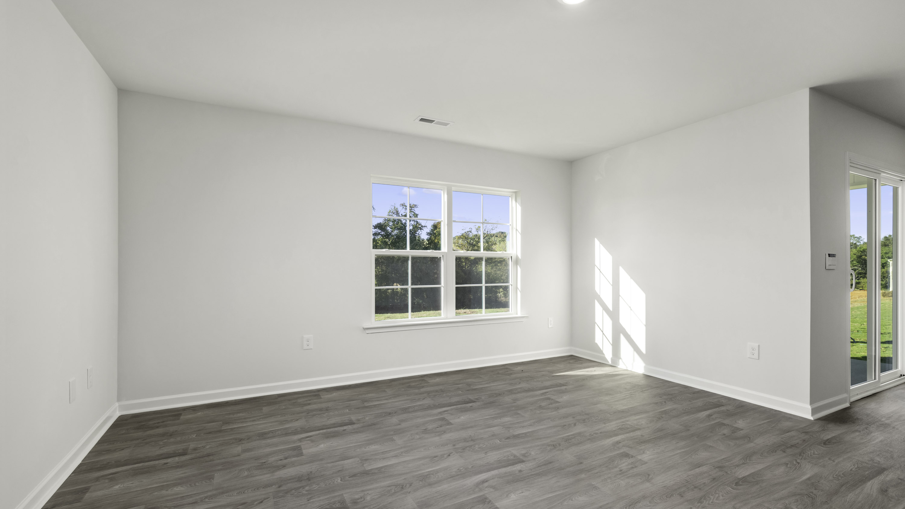 Neutral-toned room featuring wood-finish flooring, a multi-pane window, and a sliding glass door