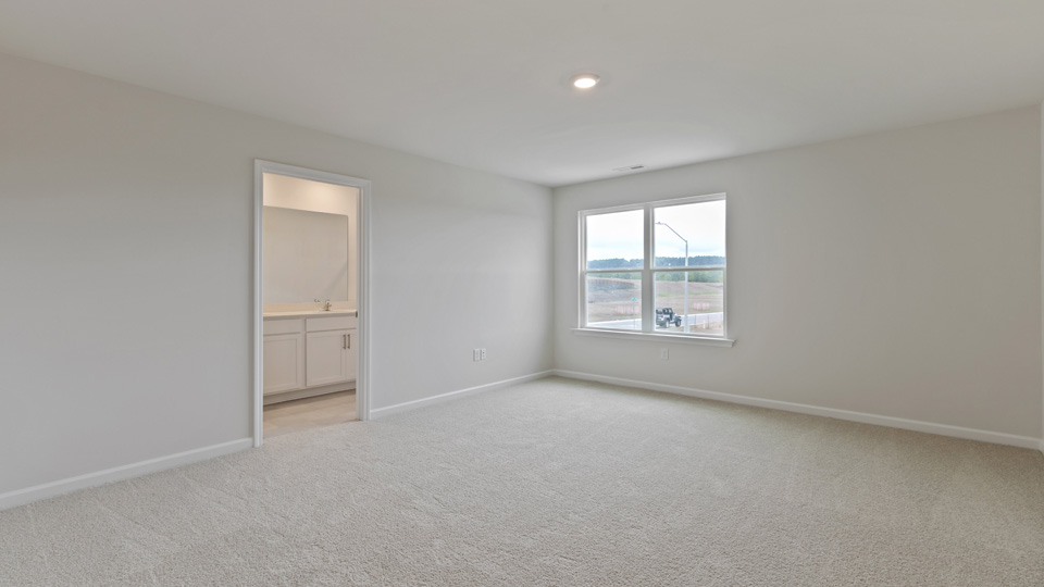 primary bedroom with two windows and carpeting, attached bath