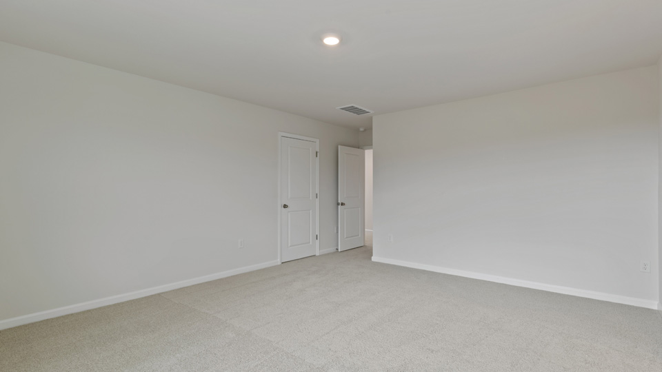 primary bedroom with two windows and carpeting, attached bath