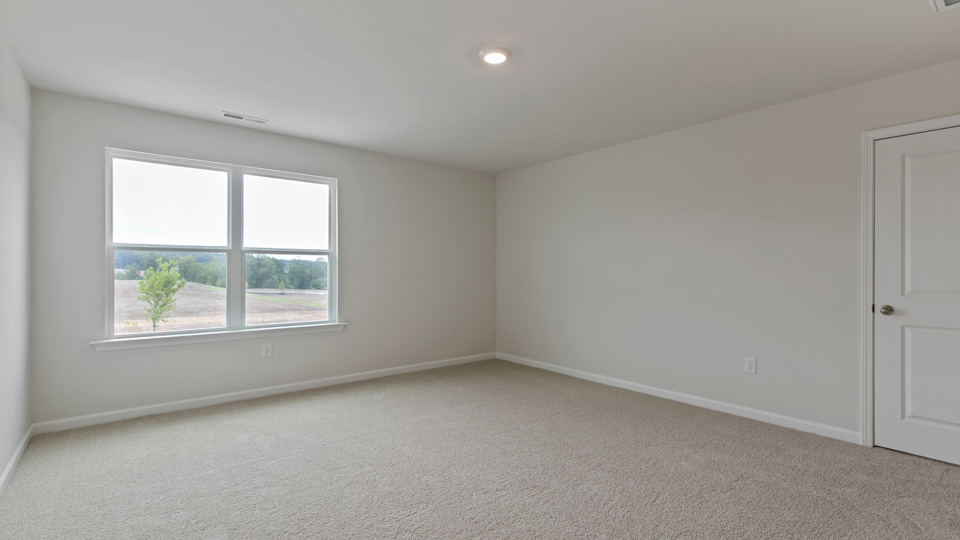 primary bedroom with two windows and carpeting, attached bath