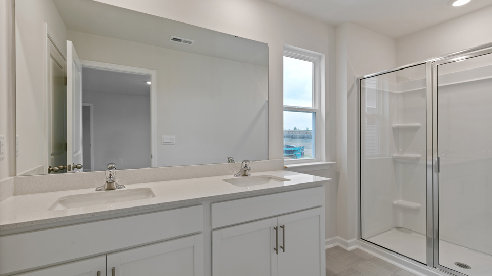 primary bathroom with walk in shower and dual vanity sinks