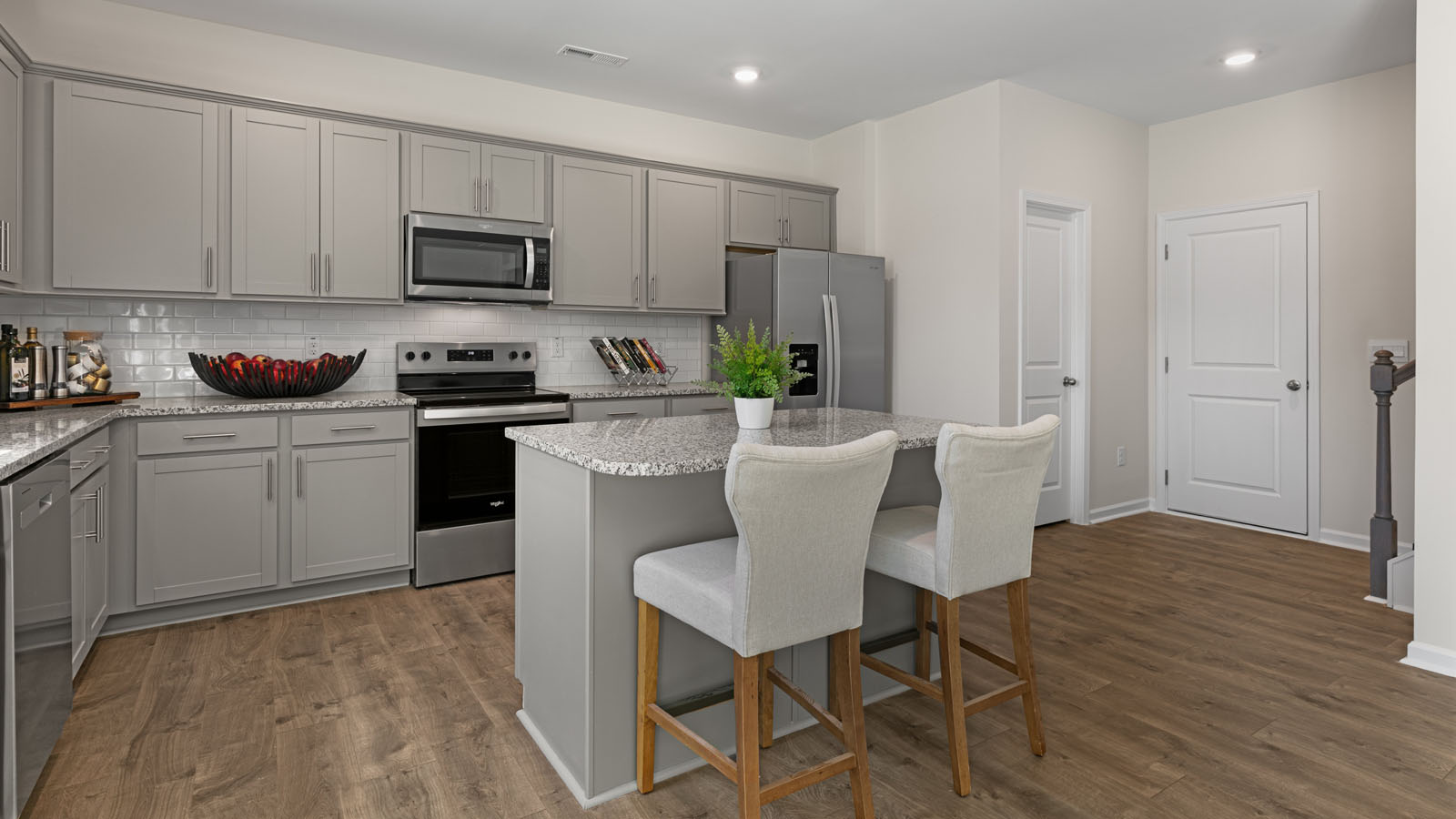 kitchen with revwood flooring, stainless steel appliances, an island and shaker style cabinets