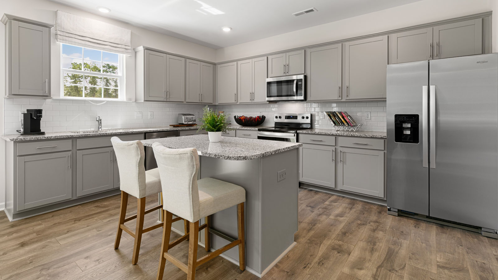 kitchen with revwood flooring, stainless steel appliances, an island and shaker style cabinets