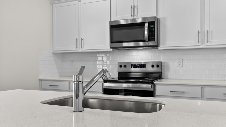kitchen with stainless steel appliances and white cabinets and quartz countertops