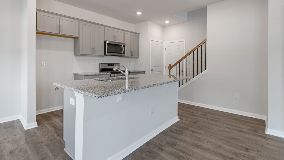 kitchen with quartz counters, kitchen island, pantry, stainless steel appliances