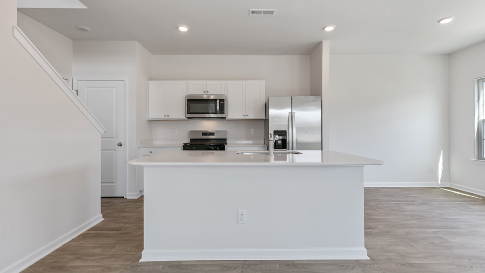 kitchen with quartz counters, kitchen island, pantry, stainless steel appliances