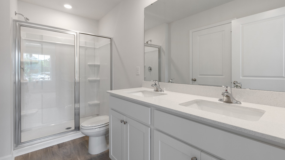 primary bathroom with walk in shower and dual vanity sinks