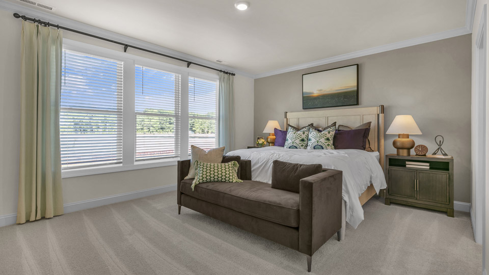 primary bedroom with two windows and carpeting, attached bath