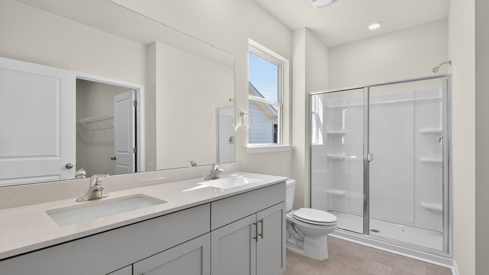 bathroom with quartz countertops and walk-in shower with glass doors