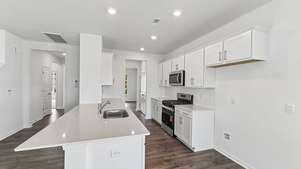 kitchen with quartz counters, kitchen island, pantry, stainless steel appliances