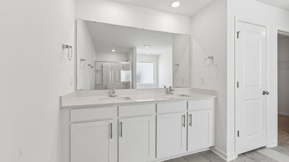 primary bathroom with walk in shower and dual vanity sinks