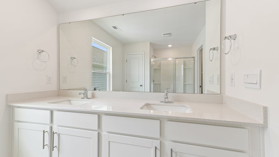 bathroom with dual vanity quartz countertops and white cabinets