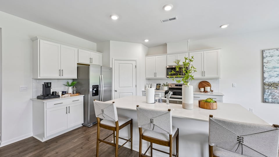 kitchen with spacious island quartz countertops and white cabinest