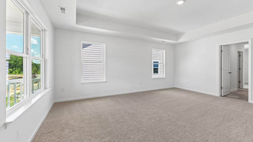 primary bedroom with two windows and carpeting, attached bath