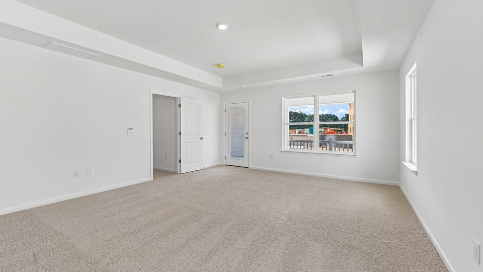 primary bedroom with two windows and carpeting, attached bath