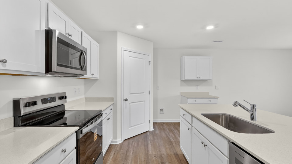 kitchen with quartz counters, kitchen island, pantry, stainless steel appliances