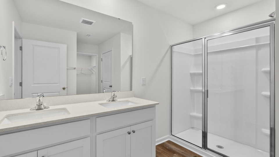 primary bathroom with walk in shower and dual vanity sinks
