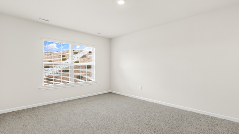 primary bedroom with two windows and carpeting, attached bath