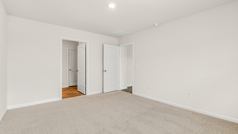 primary bedroom with two windows and carpeting, attached bath