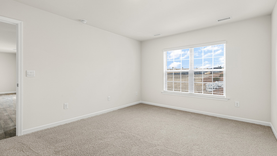 primary bedroom with two windows and carpeting, attached bath