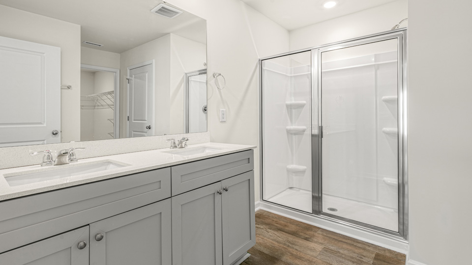 primary bathroom with walk in shower and dual vanity sinks