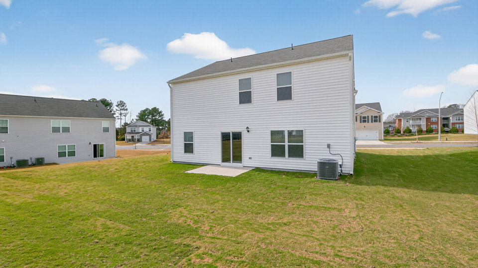 Two story home with white siding and back patio.