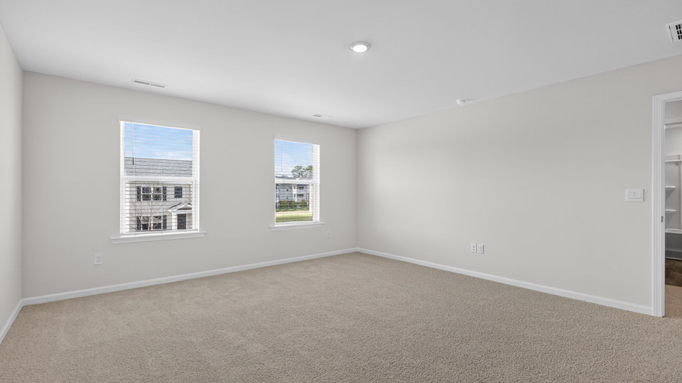 Primary bedroom with carpet and 2 windows
