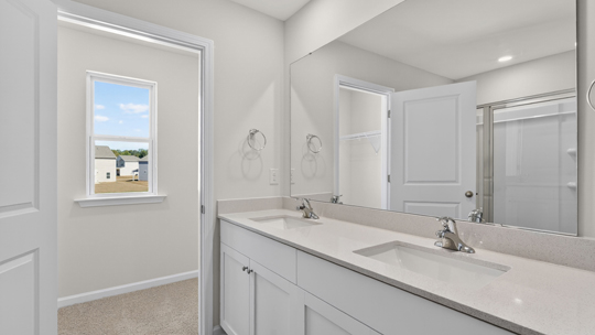 primary bathroom with white cabinets and dual vanity