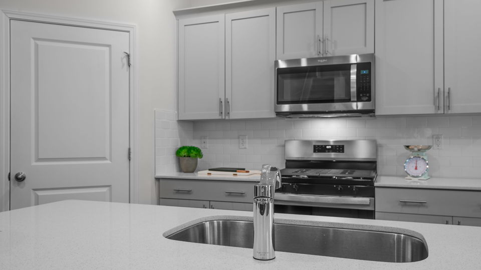 kitchen with quartz counters, kitchen island, pantry, stainless steel appliances