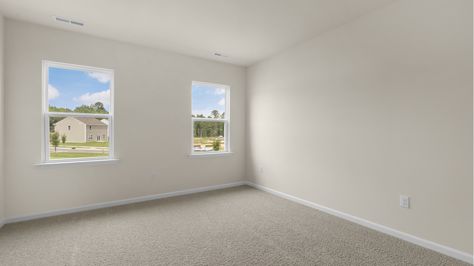primary bedroom with two windows and carpeting, attached bath