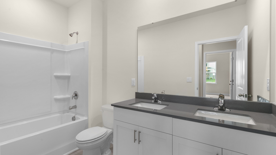 secondary bathroom with shower tub combo and dual vanity sink