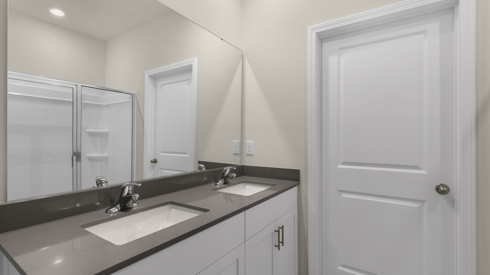 primary bathroom with walk in shower and dual vanity sinks