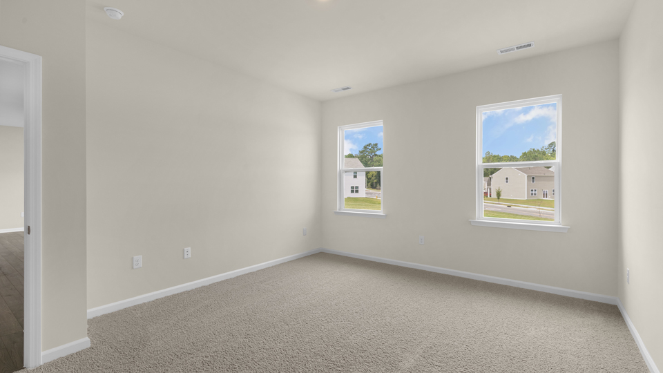 primary bedroom with two windows and carpeting, attached bath