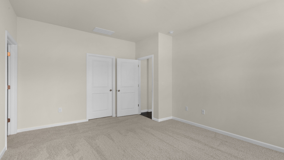 primary bedroom with two windows and carpeting, attached bath