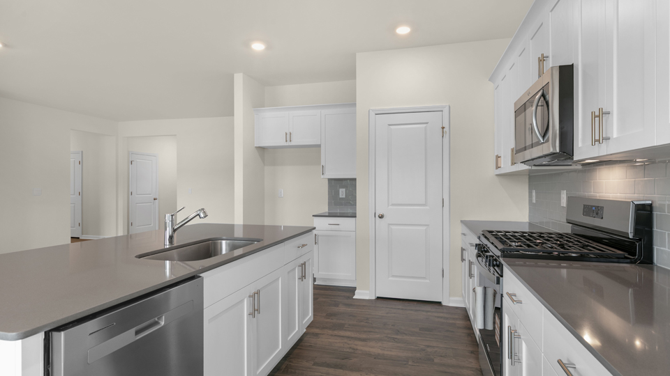 kitchen with quartz counters, kitchen island, pantry, stainless steel appliances