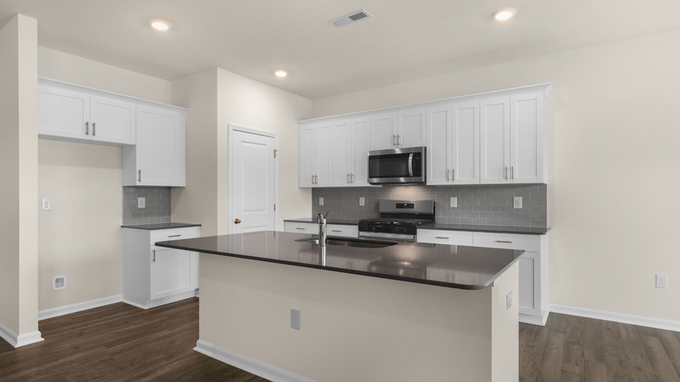 kitchen with quartz counters, kitchen island, pantry, stainless steel appliances