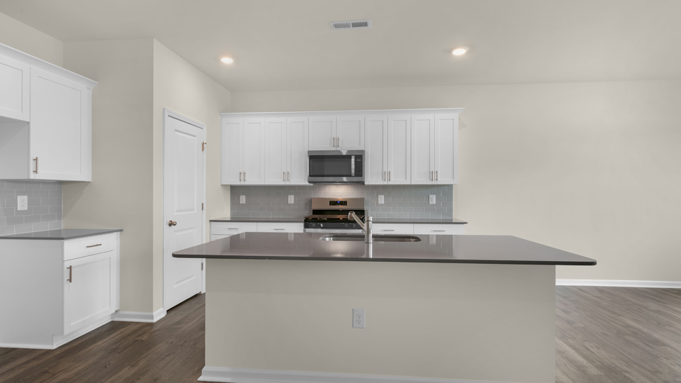 kitchen with quartz counters, kitchen island, pantry, stainless steel appliances