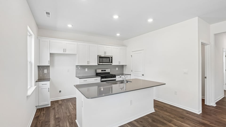 kitchen with quartz counters, kitchen island, pantry, stainless steel appliances