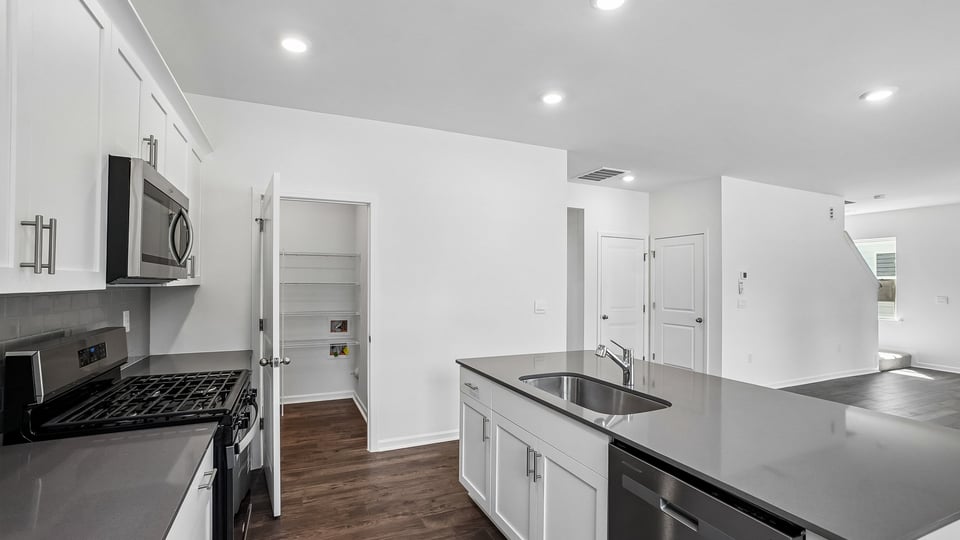 kitchen with quartz counters, kitchen island, pantry, stainless steel appliances