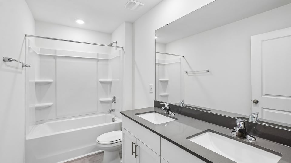 secondary bathroom with shower tub combo and dual vanity sink