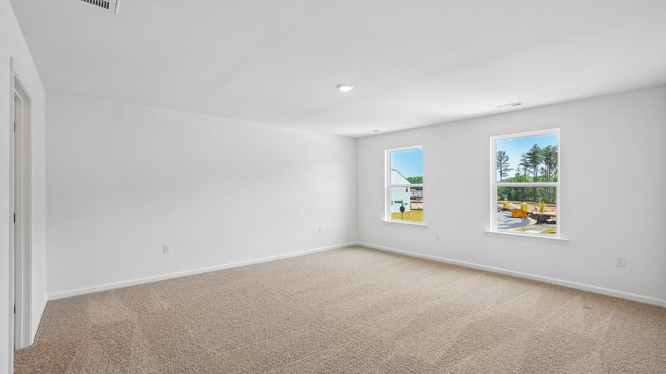 primary bedroom with two windows and carpeting, attached bath