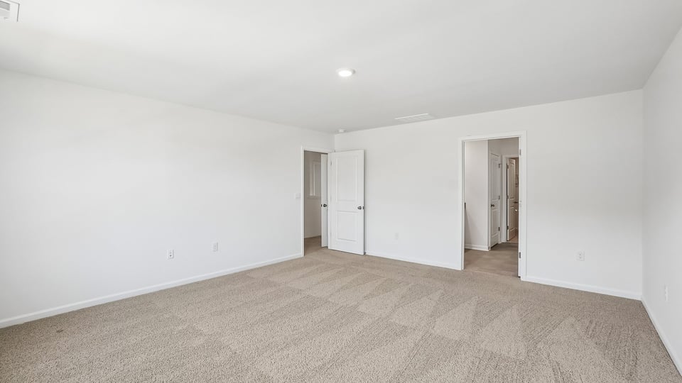 primary bedroom with two windows and carpeting, attached bath