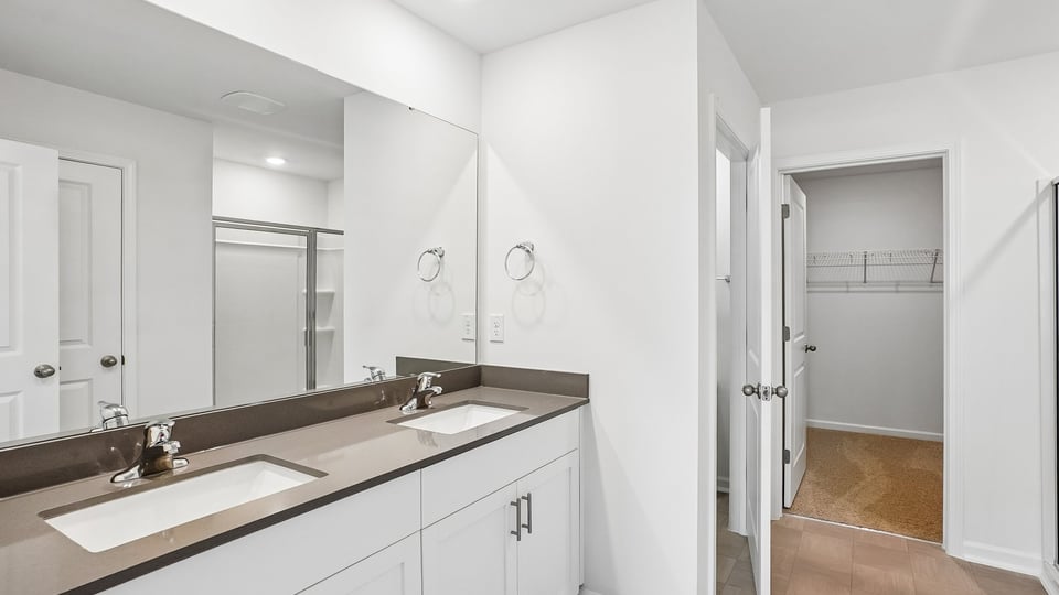 primary bathroom with walk in shower and dual vanity sinks