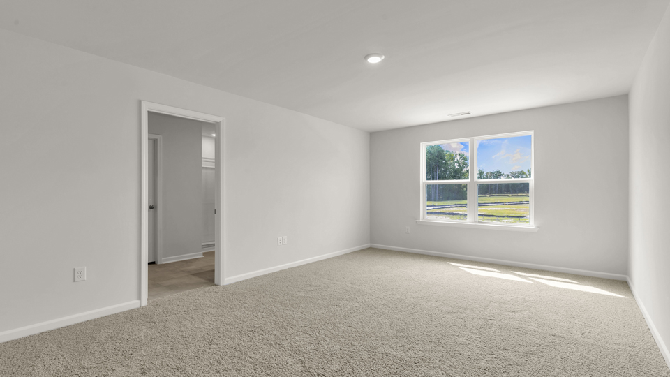 primary bedroom with two windows and carpeting, attached bath
