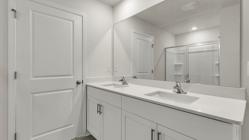primary bathroom with walk in shower and dual vanity sinks