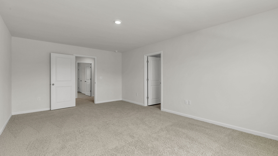 primary bedroom with two windows and carpeting, attached bath