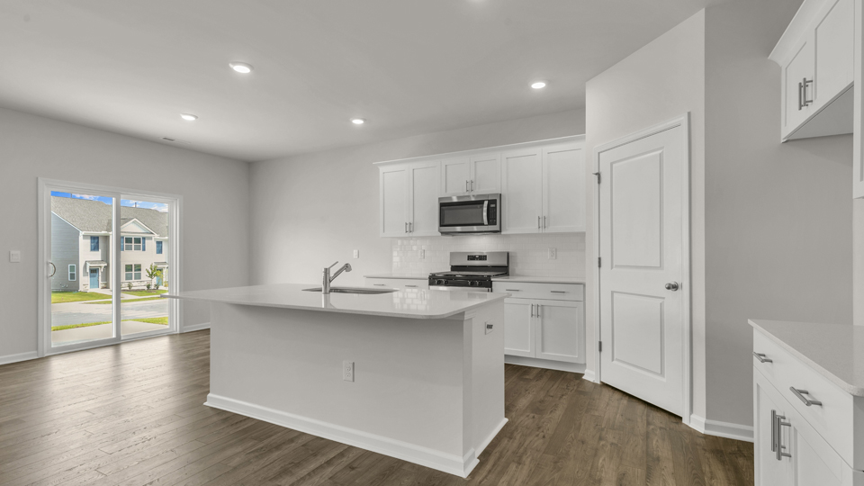 kitchen with quartz counters, kitchen island, pantry, stainless steel appliances