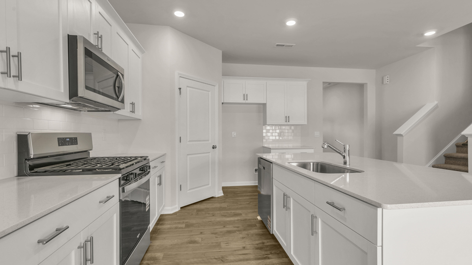 kitchen with quartz counters, kitchen island, pantry, stainless steel appliances